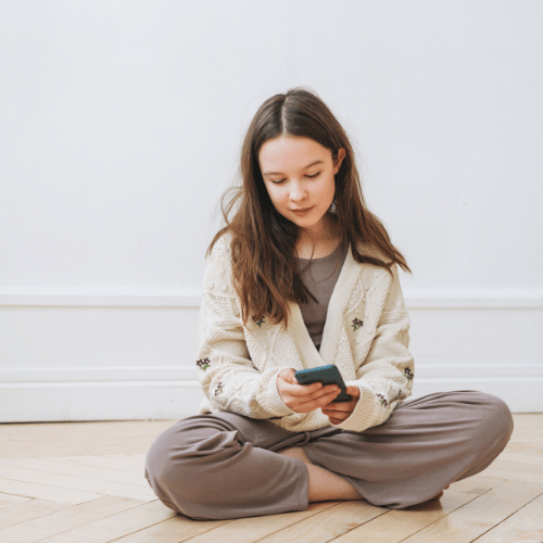 Teenage girl sitting on the side with a phone